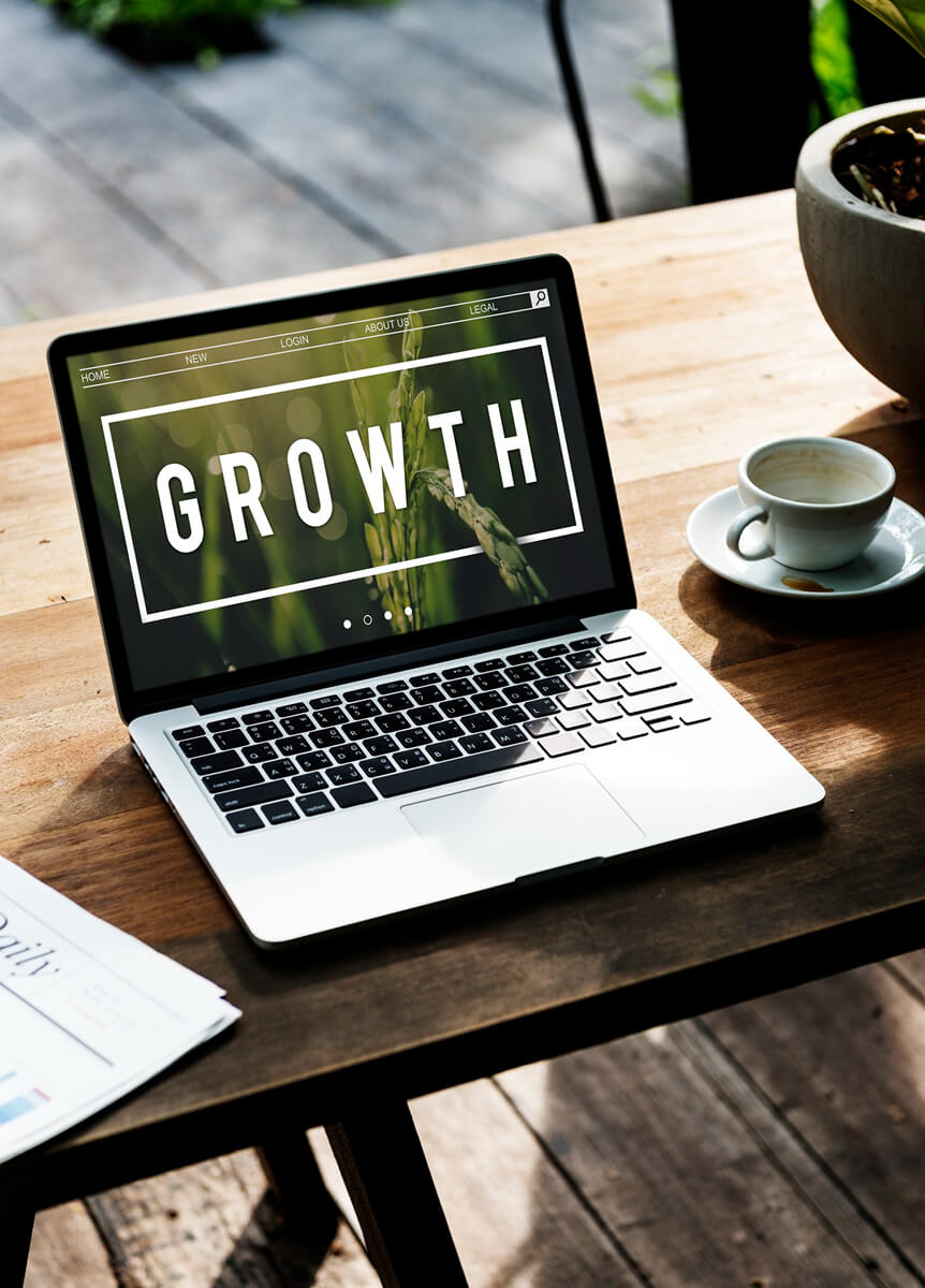 Laptop fa asztalon, a képernyőn Growth feliratú weboldal, mellette kávéscsésze
